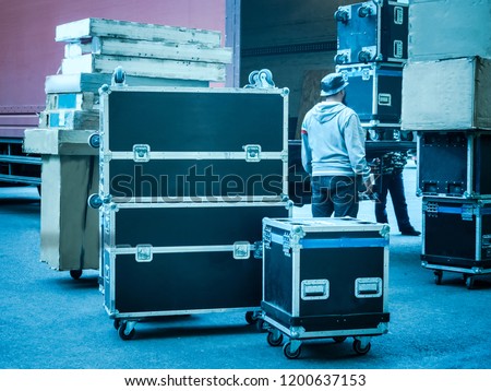Loading and unloading of concert equipment. Loading equipment in a van. Man controls the loading of equipment cases.
