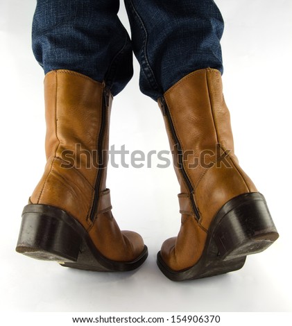 People wearing blue jeans, brown leather western cowboy boots standing on white background.