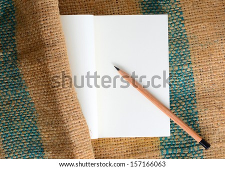 Notebook and pencil resting on brown bags, green stripes, but there are some parts of the book hit the sack off.