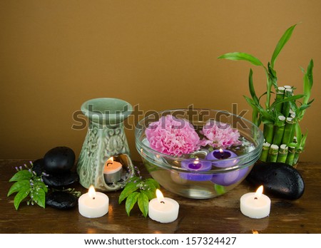 Spa candle shapes, candle, floating spheres, purple, white candles, ceramic wear perfume, glass flower bowl and floating candles, bamboo, leaves and zen stones on the ground.