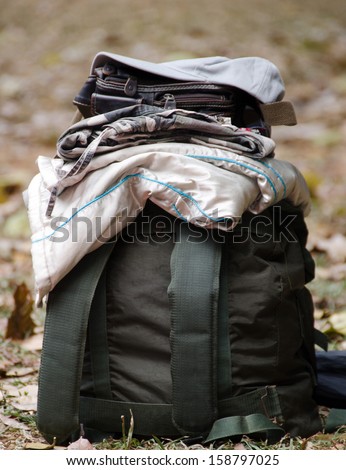 Backpack travel bag packed with clothes, fully laid out on the grass and leaves.