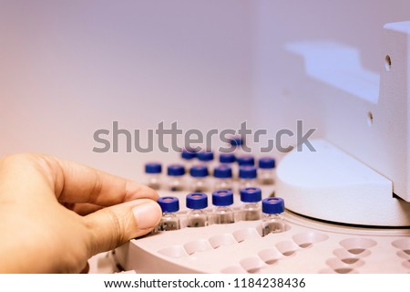 Scientist holds a chemical sample vial. People hand holding a test tube vial sets for analysis.laboratory assistant inserting laboratory glass bottle in a chromatography vial.