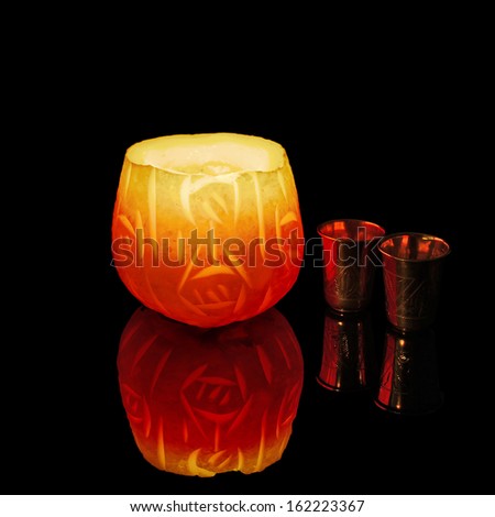 Candle and silver wine cups on a black background.