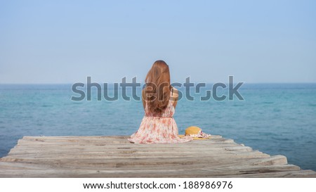 Asian beautiful women is  long hair sitting on the bridge that protrudes into the sea