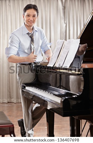 A young music composer standing near grand piano