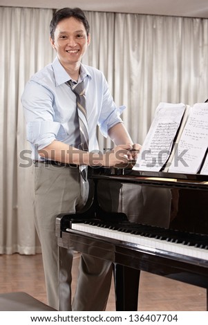 A young music composer standing near grand piano