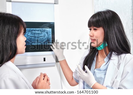 Young female dentist examining patient teeth X Ray