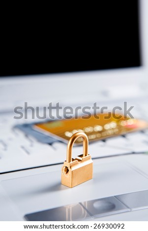 Golden lock on the laptop, with credit cards on the laptop\'s keyboard. Focus mainly on the lock.