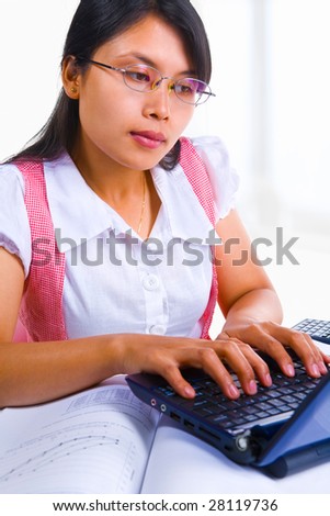 Portrait of an Asian female scholar is typing on her laptop in class