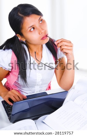 A female scholar is thinking hard in the class in front of her laptop and books