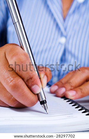 A woman's hand writing on a page of a book using a fountain pen.