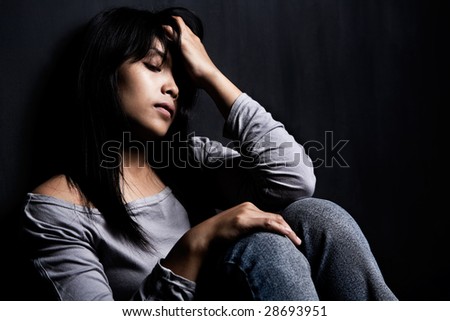 side view of stress woman leaning on dark wall