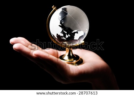Single hand holding a glass globe showing Asia and Australia continent