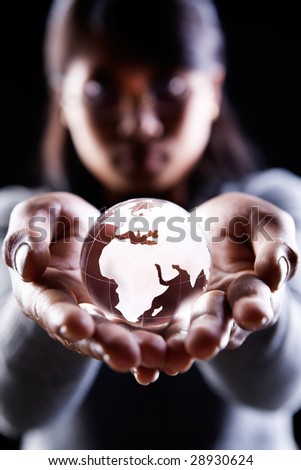 A woman holding a glass globe showing Africa. Europe and Middle East
