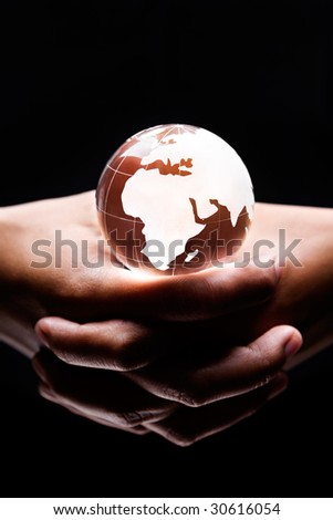 both hands holding a glass globe on it showing Africa, Europe and Middle East part