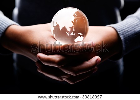 both hands holding a glass globe on it showing Asia and Australia continent