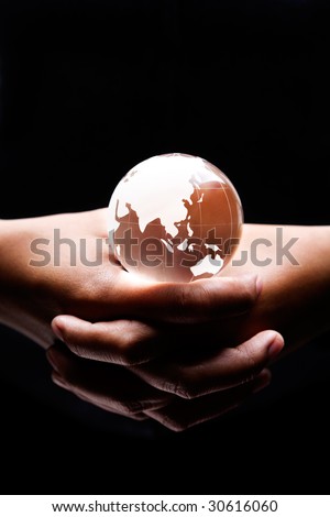 both hands holding a glass globe on it showing Asia and Australia continent