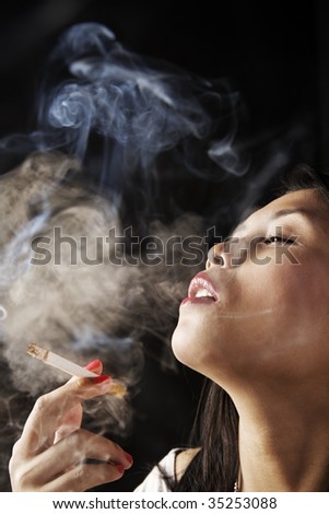 Female inhale smoke from cigarette on dark area