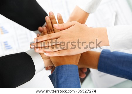 A leader hands and his employees hand in unity to express teamwork with documents on background