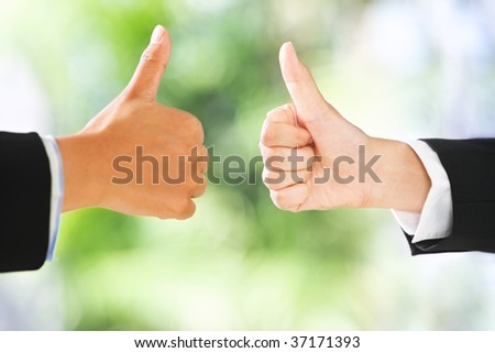 People raise thumbs up in line with green environment background. DIfferent skin tones and shallow depth of field