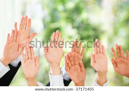 People raise their hands up to be picked up or to bid in an auction over green background