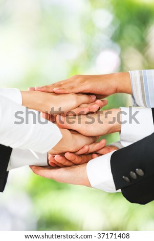 People put their hand on top of each other over the green environment background