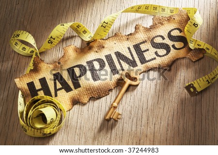 Measuring happiness concept using burnt paper with word happiness printed on it and golden key surrounded by measuring tape