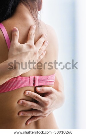 Hand supporting breast cancer victim, on the back of woman using bra with one strap only
