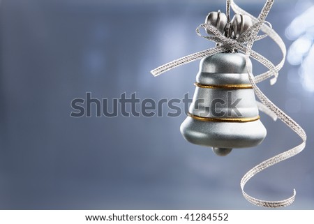 SIlver Christmas bell over bluish background with copy space