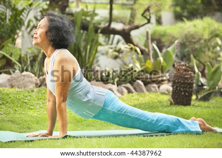 Senior old Asian woman doing yoga in park alone