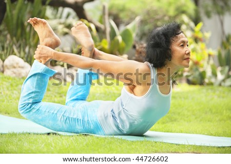 Asian senior old woman practicing yoga at garden