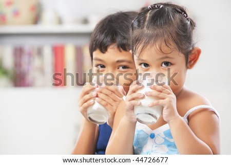 Two little boy and girl drinking milk at home