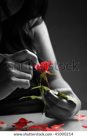 Broken heart girl picking rose petals in black and white except the rose