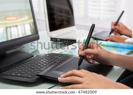 Graphic designers working in office with no face recognizable here. PS: selective focus on digital pen