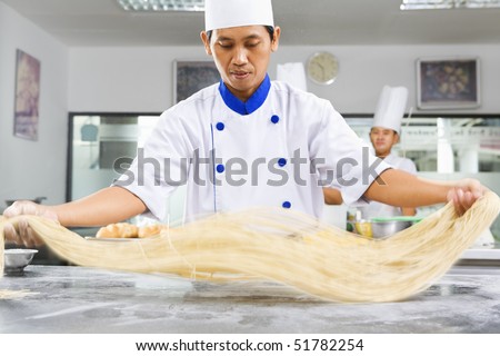 Chef making noodle in the kitchen of cooking school. ***PS : selective focus on the noodle with noticeable movement blur ***