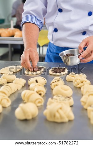 Chef hand sprinkle the chocolate chips on bread dough. PS: hand movement blur