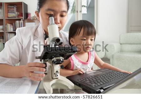 Mother busy working with microscope and her daughter busy playing laptop