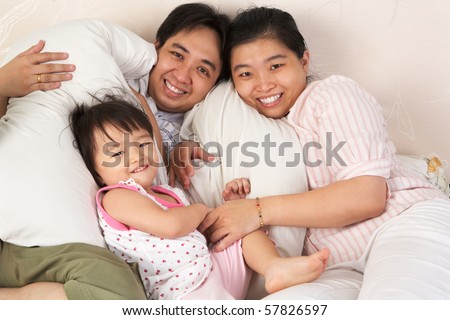Chinese family having fun on bed showing love and togetherness