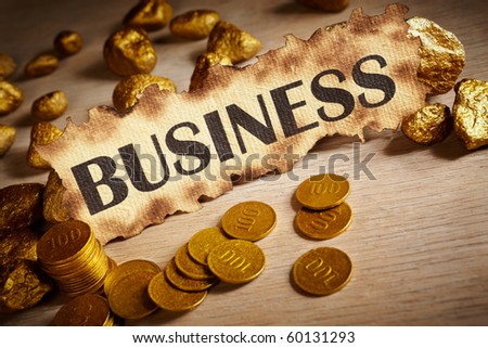 Business written on vintage paper and stack of gold coins and gold rocks