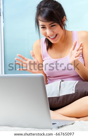 Young Asian female using laptop in her bedroom