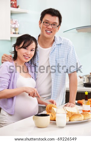 Chinese couple ( pregnant wife with her husband )  preparing breakfast in the kitchen
