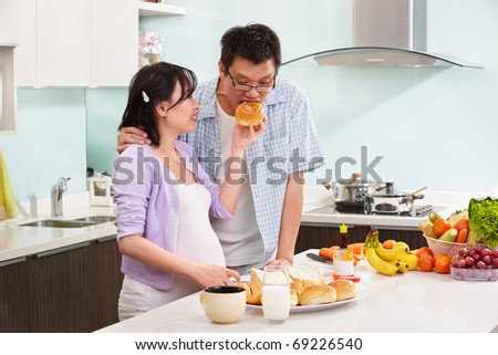 Chinese couple ( pregnant wife with her husband )  preparing breakfast in the kitchen