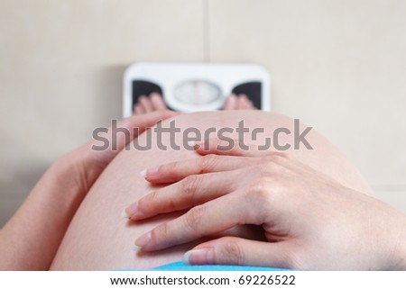 Pregnant lady measuring her weight, taken from high angle