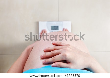 Pregnant lady measuring her weight, taken from high angle