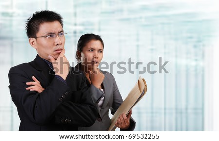 Two Asian business people thinking and looking to empty space with blur  glass window background.