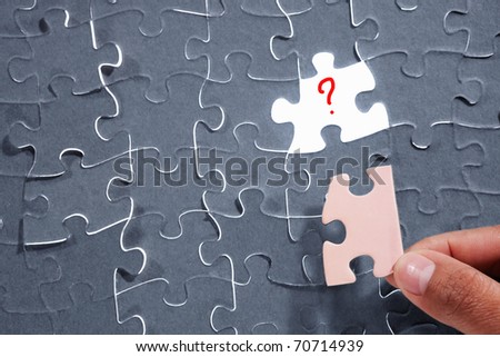 Finger holding the wrong piece for the last missing puzzle piece