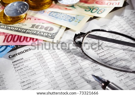 Glasses over the foreign exchange sheet with money from different countries on edge