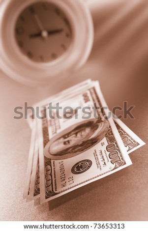 Time is money concept, with US dollar paper in front of a green clock in sepia color