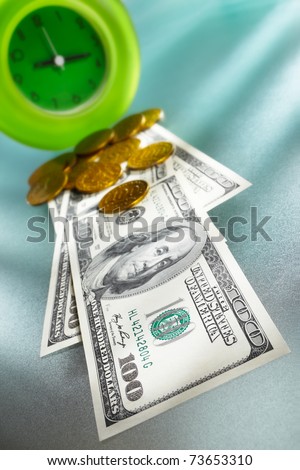 Time is money concept, with US dollar paper in front of a green clock