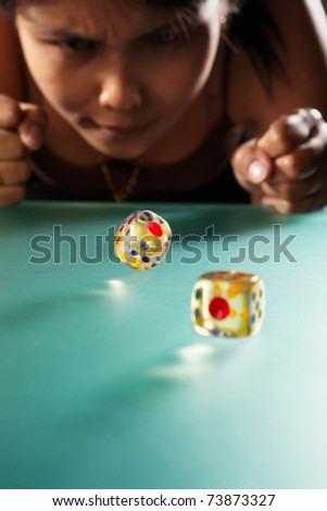 Young Asian woman expressing her hope to get big number on rolling dices